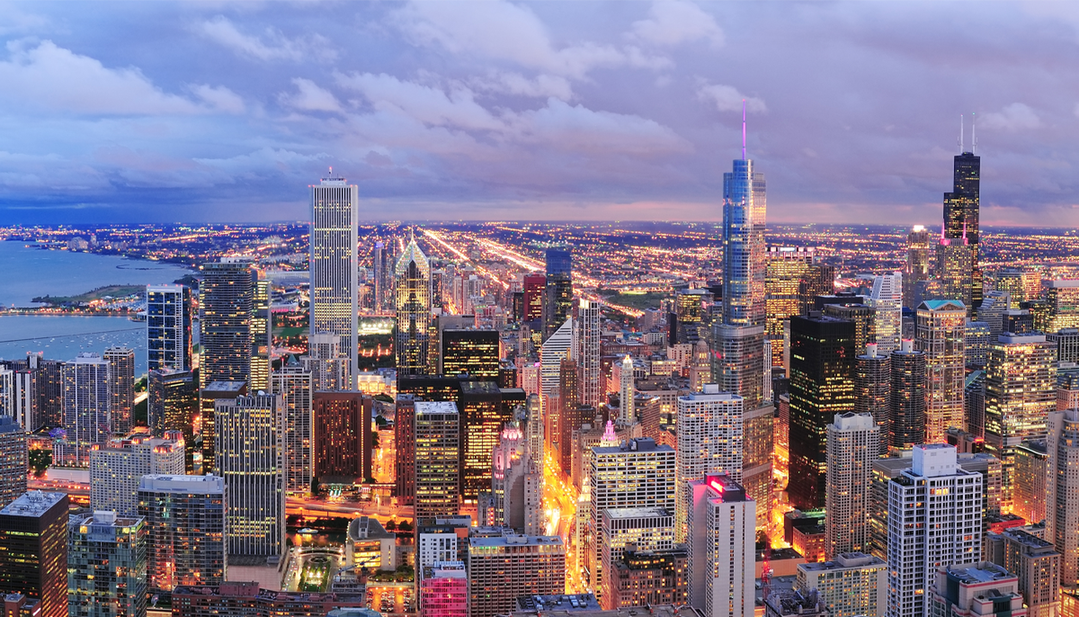 Downtown Chicago in Vogelperspektive in der Dämmerung, Hochhäuser hell erleuchtet und eine wolkiger Himmelshintergrund