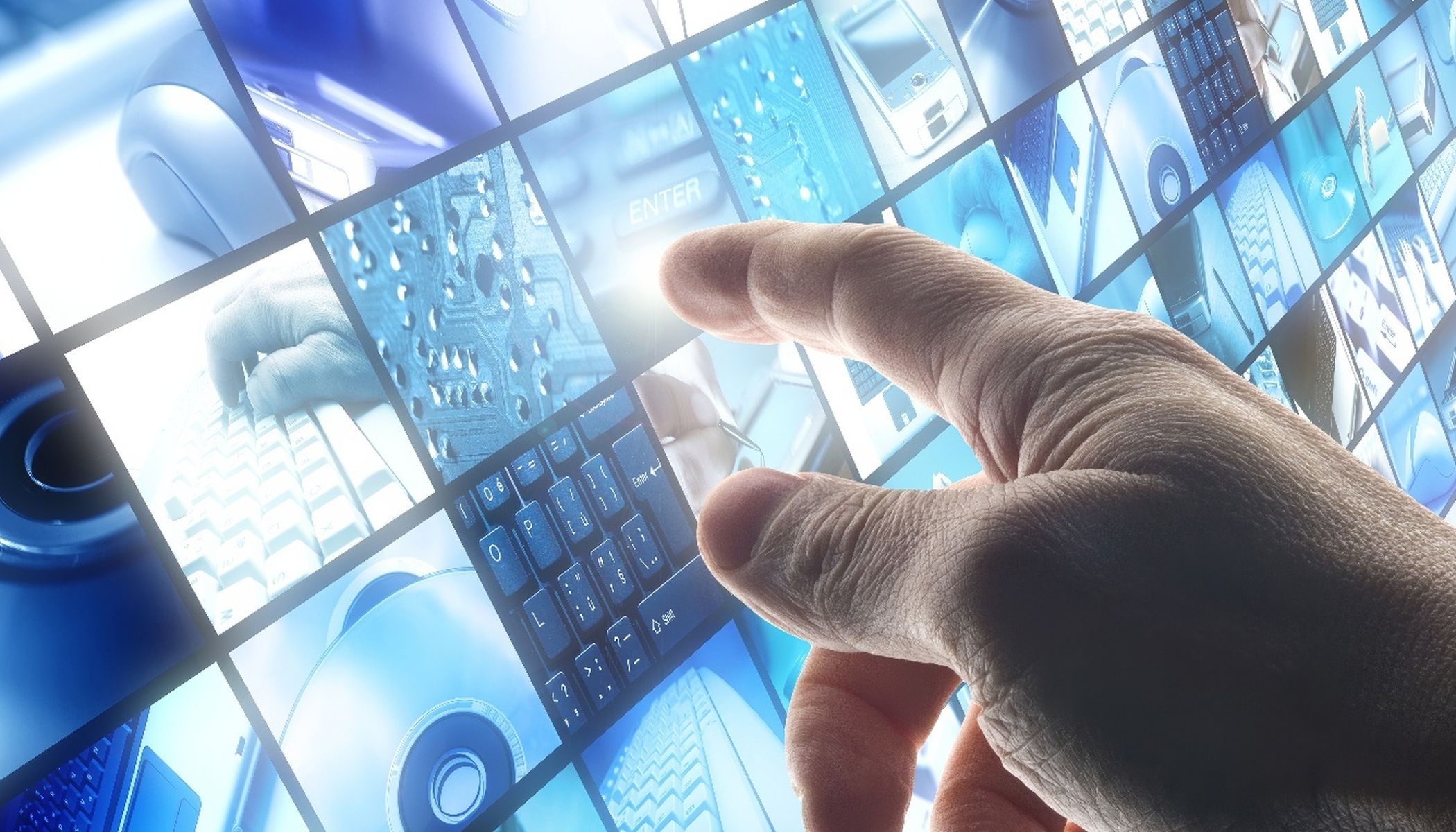 A hand touches a digital screen consisting of several juxtaposed images depicting technical elements such as keyboards, a computer mouse, circuit boards and an enter key. The images are in a blue tone.